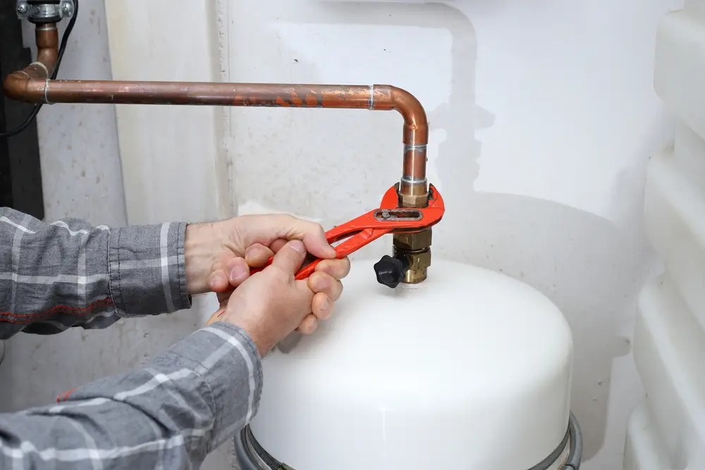Technician tightening a fitting on a boiler tank